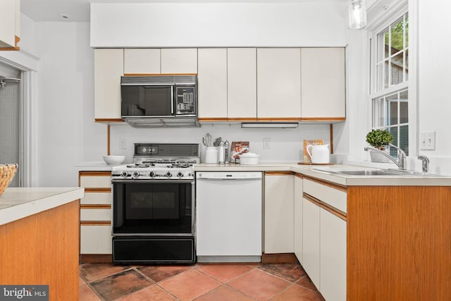 kitchen with white dishwasher, black microwave, gas range oven, a sink, and light countertops