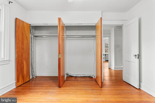 unfurnished bedroom with light wood-style floors, a closet, and baseboards