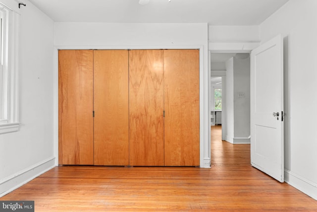 unfurnished bedroom with light wood-style floors, a closet, and baseboards