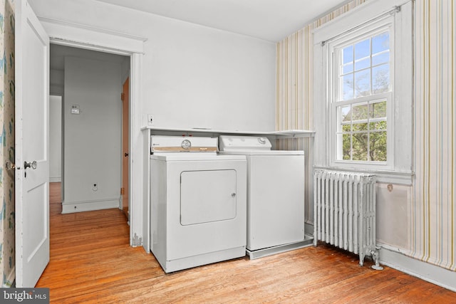 laundry room featuring radiator heating unit, washing machine and dryer, and light wood-style flooring