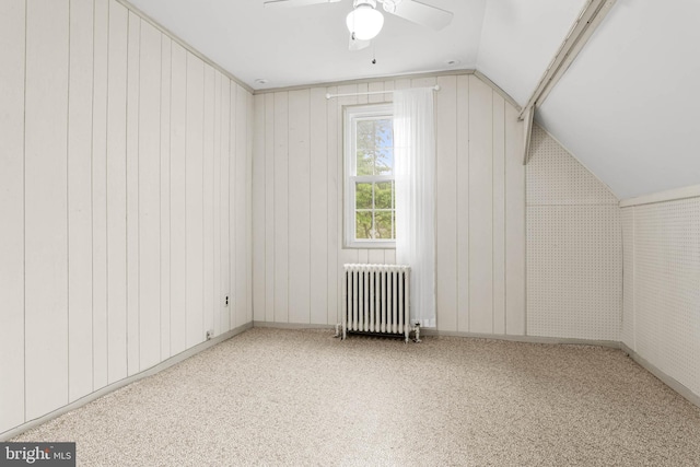bonus room with radiator heating unit, ceiling fan, carpet, lofted ceiling, and wooden walls