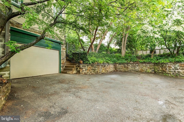 garage featuring fence and driveway