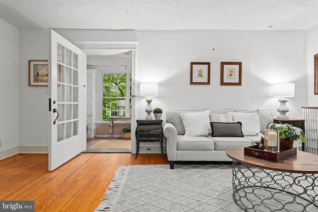 living room with light wood-style flooring, a textured ceiling, and baseboards