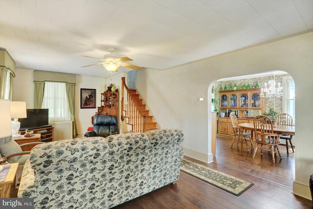 living room with arched walkways, stairs, ceiling fan, dark wood-style flooring, and baseboards