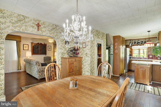 dining room featuring arched walkways, wallpapered walls, dark wood-style floors, and a chandelier