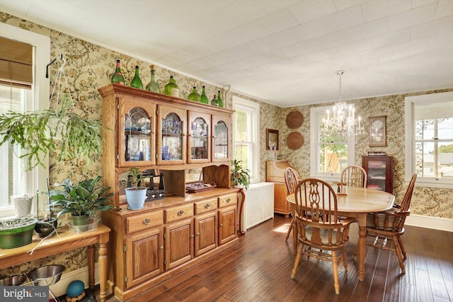 dining room with wallpapered walls, dark wood finished floors, a chandelier, baseboards, and ornamental molding
