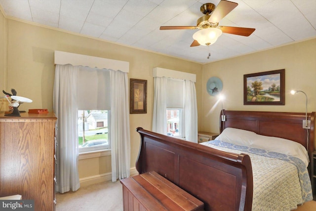 bedroom featuring light colored carpet, baseboards, and a ceiling fan