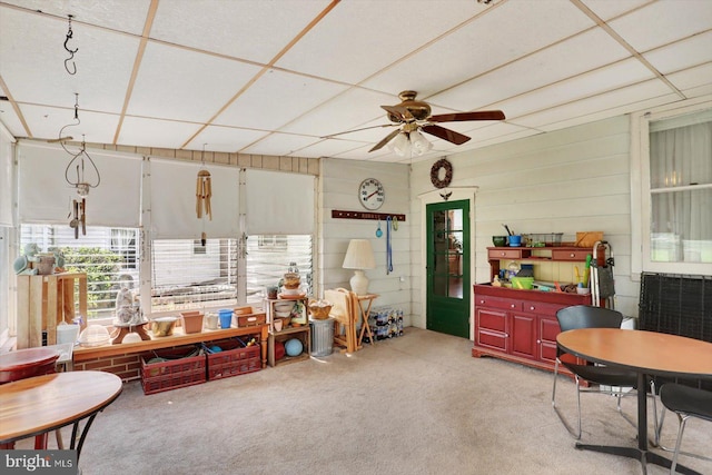 interior space featuring ceiling fan, light colored carpet, and a drop ceiling