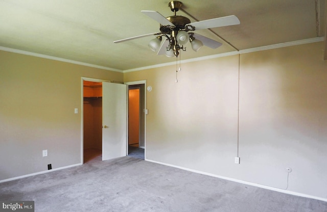 spare room featuring carpet, a ceiling fan, baseboards, and crown molding