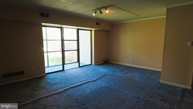 carpeted empty room featuring baseboards, rail lighting, and ornamental molding