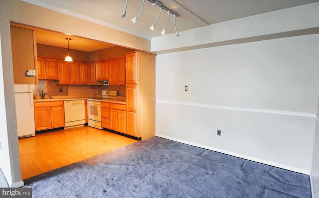 kitchen featuring white appliances, a sink, light carpet, pendant lighting, and light countertops