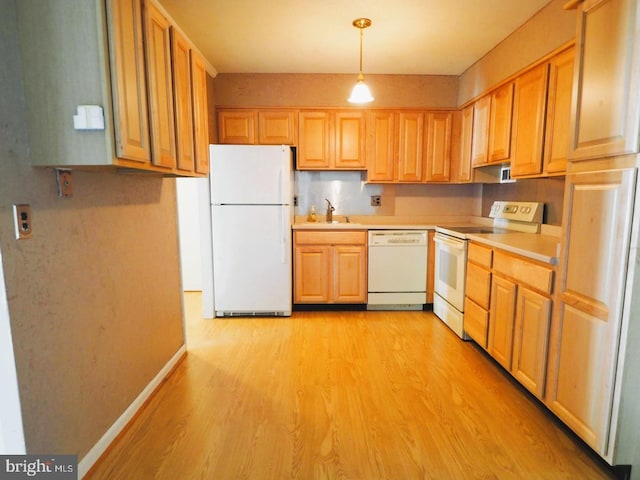 kitchen with white appliances, a sink, light wood-style flooring, light countertops, and baseboards