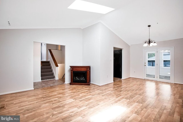 11545 Tomahawk Trl W, Lusby, MD 20657 - unfurnished living room with light wood-style flooring, a chandelier, a fireplace, stairway, and a skylight