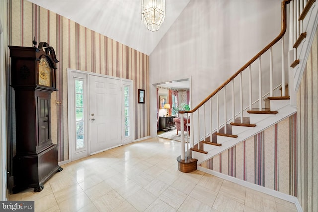 foyer featuring wallpapered walls, stairs, baseboards, a chandelier, and tile patterned floors