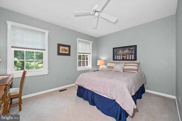carpeted bedroom featuring multiple windows, baseboards, and a ceiling fan