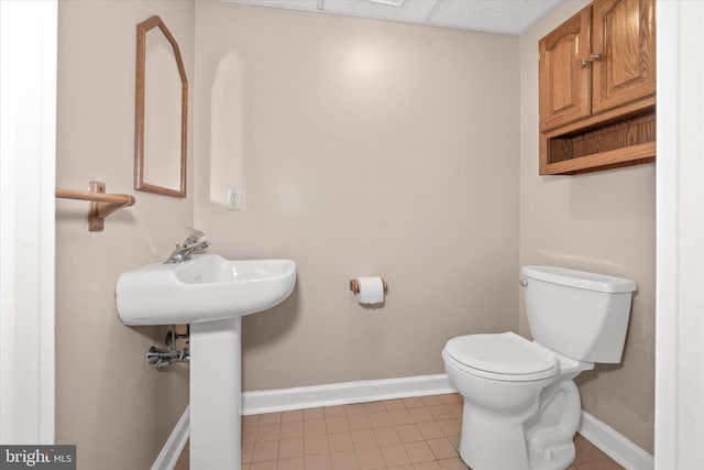 half bath with tile patterned flooring, toilet, and baseboards