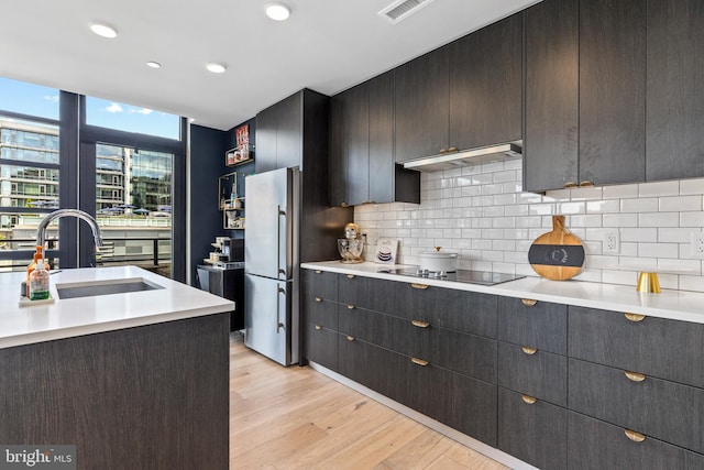 1300 4th St SE Unit 404, Washington, DC 20003 - kitchen with freestanding refrigerator, a sink, under cabinet range hood, light countertops, and decorative backsplash