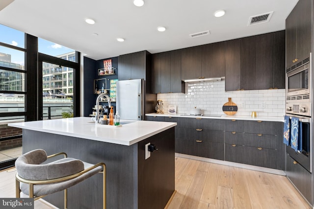 1300 4th St SE Unit 404, Washington, DC 20003 - kitchen with appliances with stainless steel finishes, light countertops, tasteful backsplash, light wood finished floors, and a sink