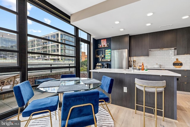 1300 4th St SE Unit 404, Washington, DC 20003 - kitchen featuring freestanding refrigerator, floor to ceiling windows, light countertops, decorative backsplash, and a kitchen breakfast bar