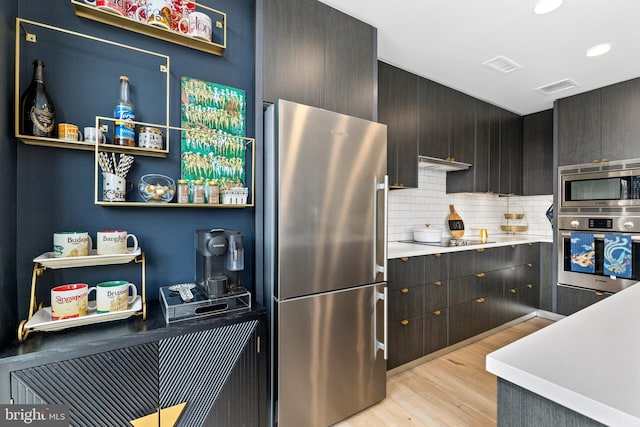 1300 4th St SE Unit 404, Washington, DC 20003 - kitchen with stainless steel appliances, light wood finished floors, backsplash, under cabinet range hood, and light countertops