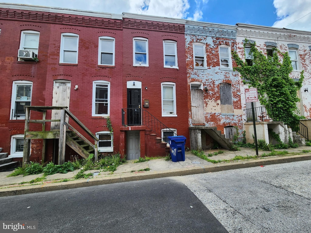 view of front facade with brick siding, cooling unit, and stairway