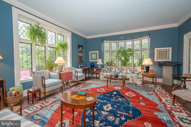 living area with healthy amount of natural light, wood finished floors, crown molding, and baseboards