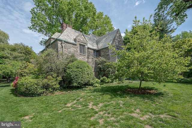 view of home's exterior featuring a high end roof, a chimney, a yard, and stone siding