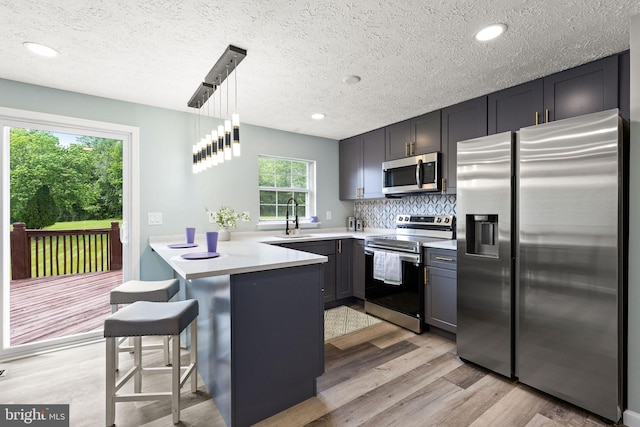 1207 Blithe Ct, Upper Marlboro, MD 20774 - kitchen featuring stainless steel appliances, a sink, a peninsula, light wood-style flooring, and decorative backsplash