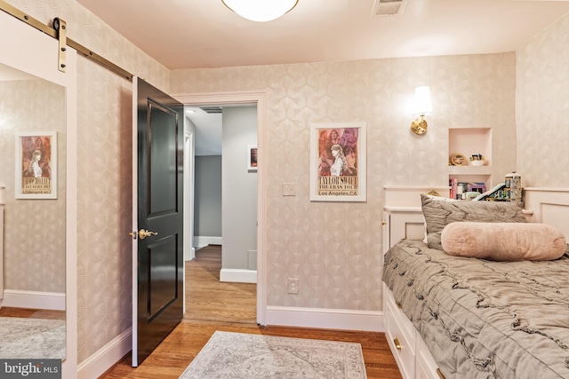 3503 Norris Pl, Alexandria, VA 22305 - bedroom featuring wood finished floors, wallpapered walls, and a barn door
