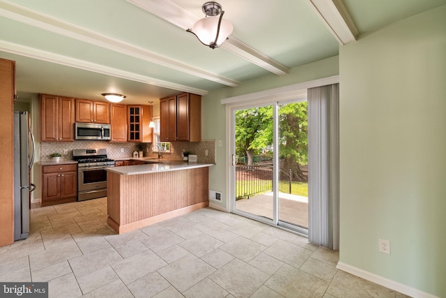 kitchen featuring appliances with stainless steel finishes, decorative backsplash, a peninsula, beam ceiling, and a sink