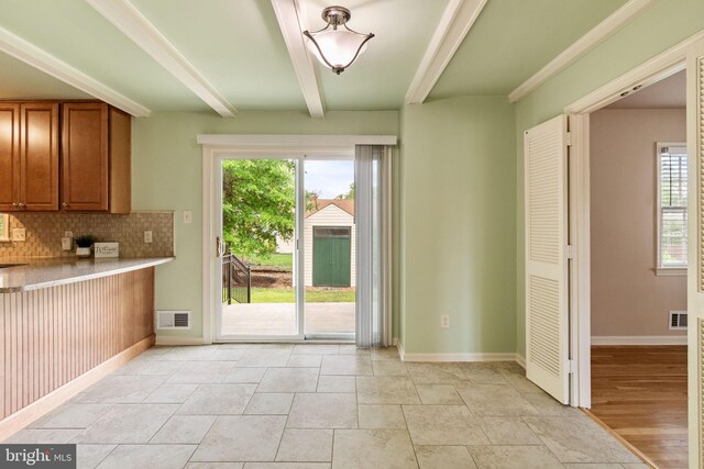 kitchen with brown cabinets, decorative backsplash, healthy amount of natural light, beamed ceiling, and baseboards