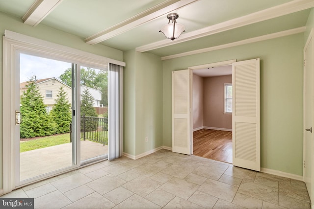 spare room featuring beam ceiling, baseboards, and light stone finish flooring