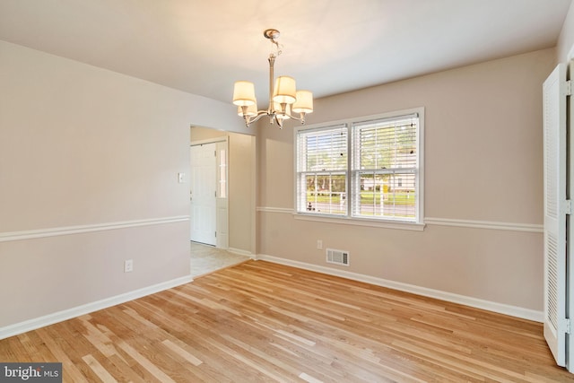unfurnished room featuring a chandelier, light wood finished floors, and baseboards