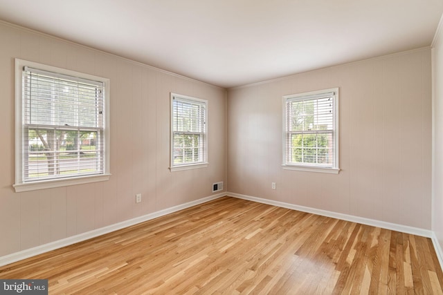 unfurnished room featuring light wood-style floors, healthy amount of natural light, baseboards, and ornamental molding