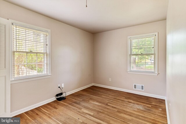 empty room with healthy amount of natural light, light wood finished floors, and baseboards