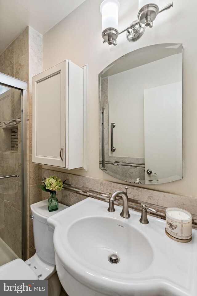 bathroom featuring a sink, tiled shower, and toilet