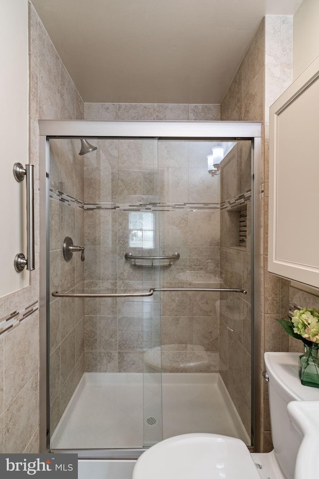 full bathroom with tile walls, toilet, and a stall shower