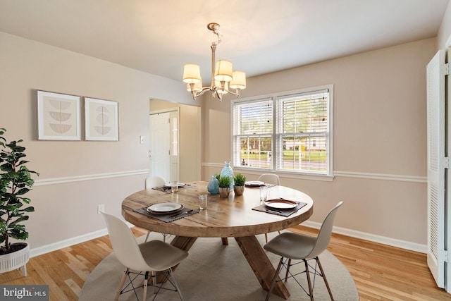 dining room with a chandelier, light wood finished floors, and baseboards
