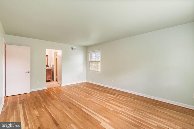 unfurnished bedroom featuring light wood finished floors, baseboards, and ensuite bath