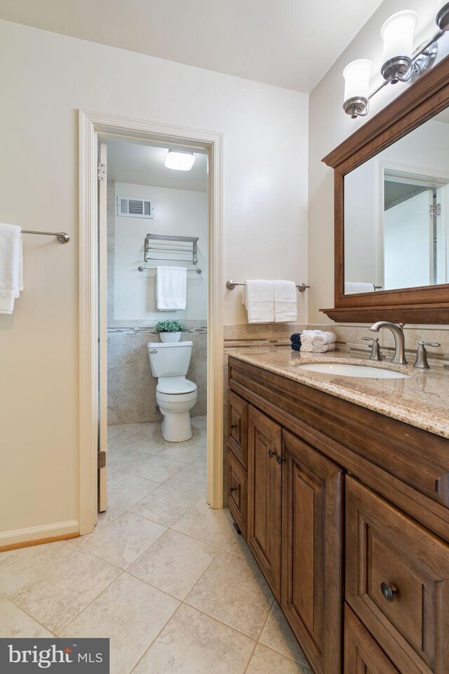 bathroom featuring toilet, tile walls, vanity, and tile patterned floors