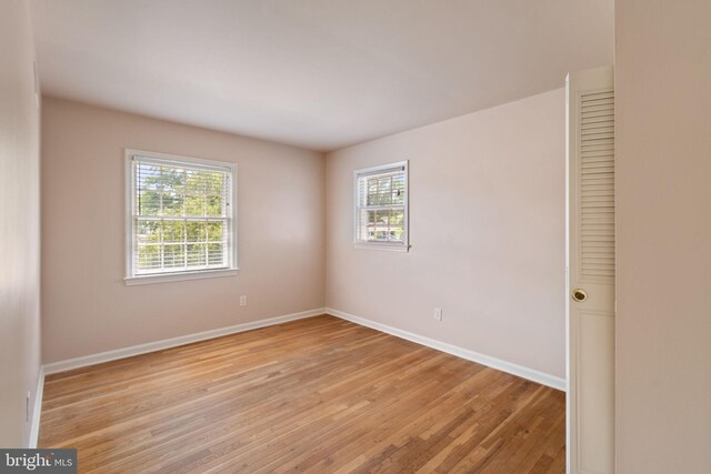 spare room featuring healthy amount of natural light, light wood-type flooring, and baseboards