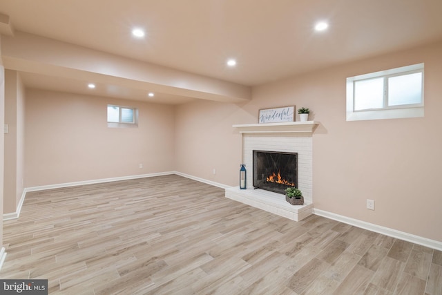 unfurnished living room featuring a brick fireplace, light wood-type flooring, recessed lighting, and baseboards