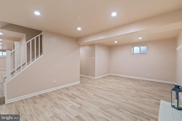 basement featuring light wood-style flooring, recessed lighting, stairway, and baseboards