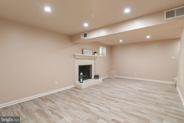 unfurnished living room with recessed lighting, light wood-type flooring, baseboards, and a brick fireplace