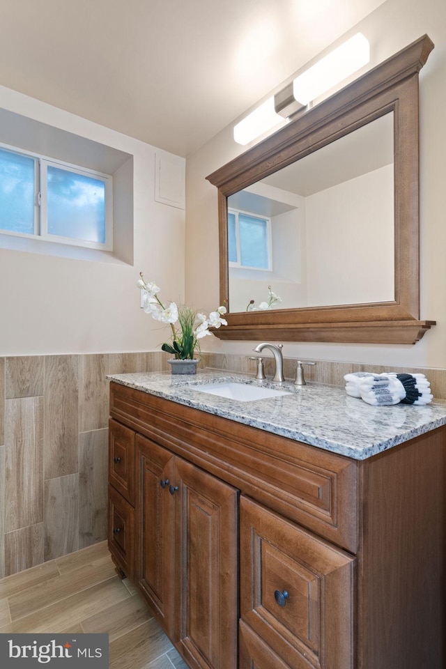 bathroom with vanity, tile walls, and a wainscoted wall
