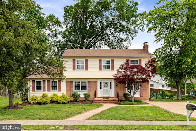 colonial inspired home featuring a chimney and brick siding