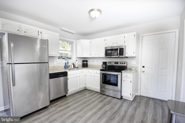 411 S Blvd, Salisbury, MD 21801 - kitchen with appliances with stainless steel finishes, white cabinets, light stone counters, light wood-style flooring, and a sink