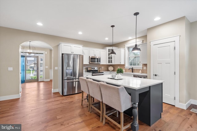 843 Summer Breeze Path, Cochranville, PA 19330 - kitchen with stainless steel appliances, arched walkways, white cabinetry, a center island, and light wood-style floors
