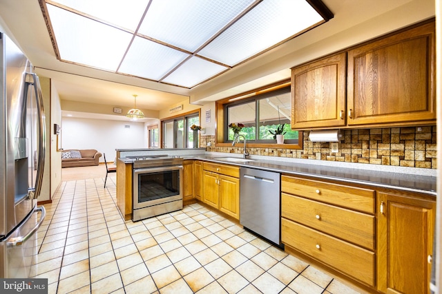 8323 Morningside Dr, Manassas, VA 20112 - kitchen featuring appliances with stainless steel finishes, a sink, backsplash, a peninsula, and light tile patterned floors