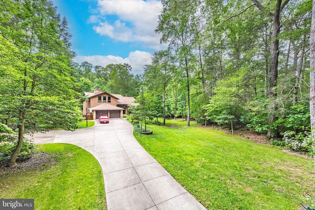 8323 Morningside Dr, Manassas, VA 20112 - view of front of home featuring a front yard, concrete driveway, a chimney, and a forest view